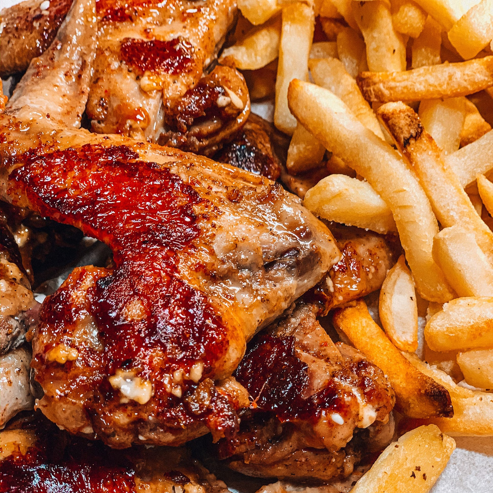 Close-up of crispy, glazed chicken wings and golden french fries from Brenda's Sports Bar & Grill.
