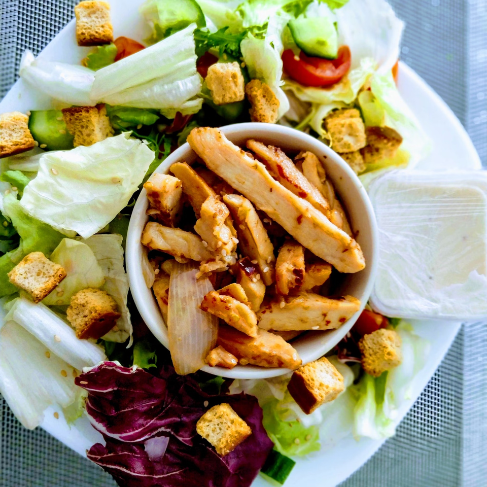 Overhead view of a chicken salad with croutons and a side of dressing at Brenda's Sports Bar & Grill.