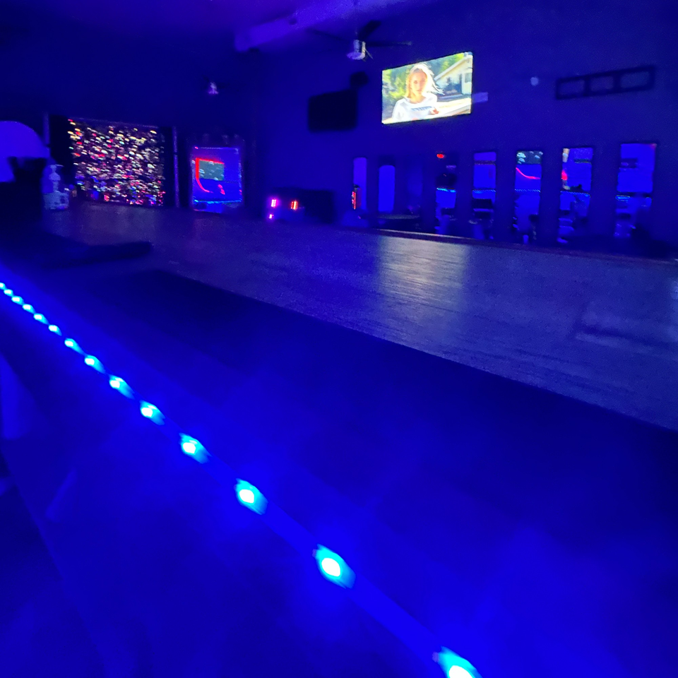 Brenda's Sports Bar & Grill interior with blue lighting, a TV screen, and illuminated strip lights.